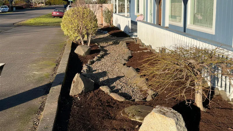 Front bed with fresh bark and a reset rock line