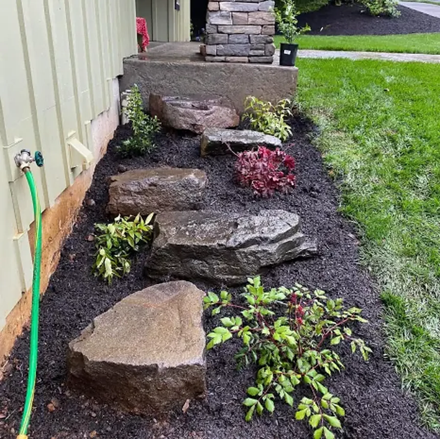 Planting bed with fresh bark and boulders along a Salem house